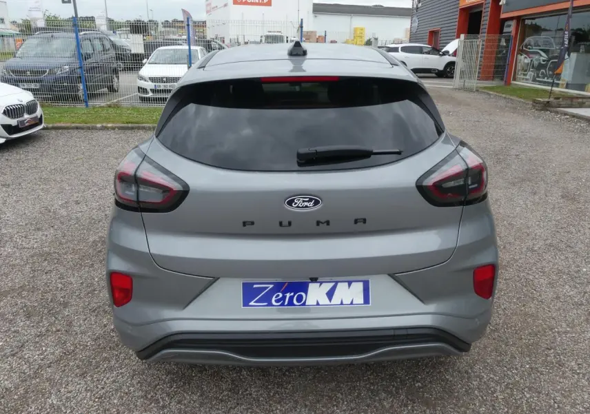 Vue arrière d'un Ford Puma gris métallisé 2025 avec feux LED et vitre arrière teintée sur parking.