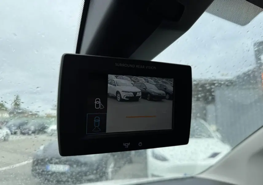 Écran de caméra de recul dans un Citroën Berlingo blanc, vue intérieure sous pluie avec voitures en arrière-plan.