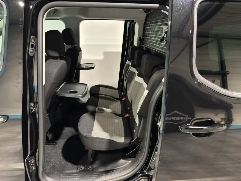 Vue latérale droite sur l'intérieur du Citroën Berlingo noir, montrant la banquette arrière et tablettes rabattables.