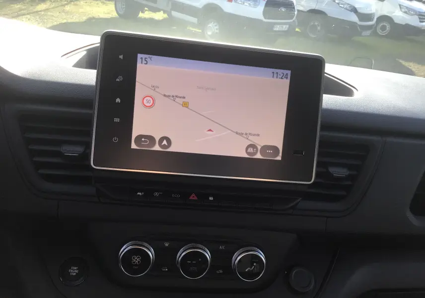 Vue intérieure centrée sur l'écran tactile 8'' du tableau de bord du Renault Trafic Fourgon blanc, avec commandes de climatisation visibles.