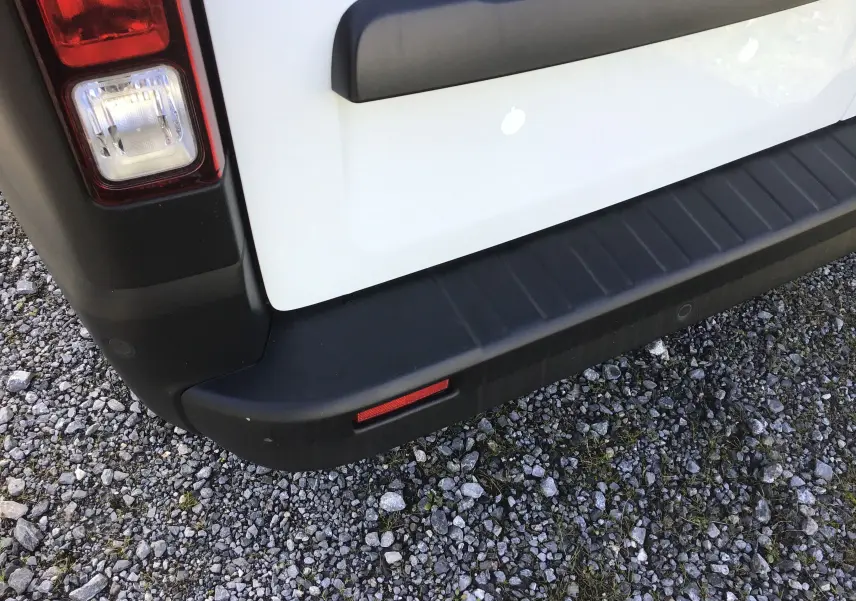 Gros plan sur l'angle arrière gauche du Renault Trafic Fourgon blanc, montrant le feu arrière et le pare-chocs noir.