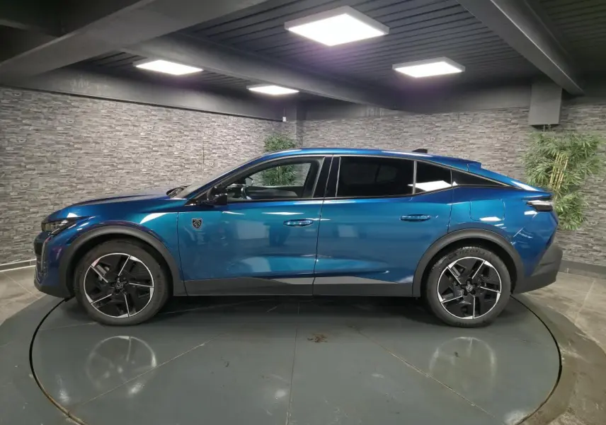 Vue de profil côté gauche d'une Peugeot 408 hybride rechargeable bleu métallisé avec jantes alliage 19 pouces dans un showroom.