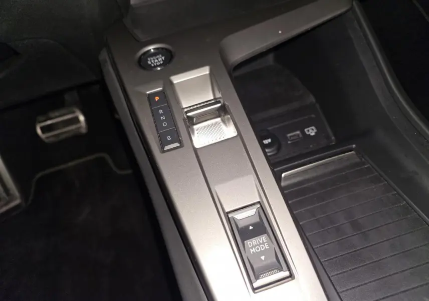 Vue rapprochée de la console centrale grise avec sélecteur de boîte auto et bouton Drive Mode dans une Peugeot 408 bleu.