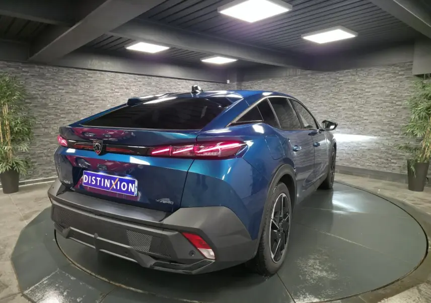 Vue 3/4 arrière droite d'une Peugeot 408 hybride rechargeable bleu métallisé avec feux arrière LED griffés et jantes alliage 19 pouces.