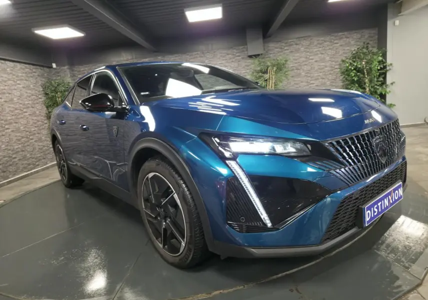 Vue 3/4 avant droite d'une Peugeot 408 hybride rechargeable bleu métallisé avec calandre distinctive et feux LED griffés.