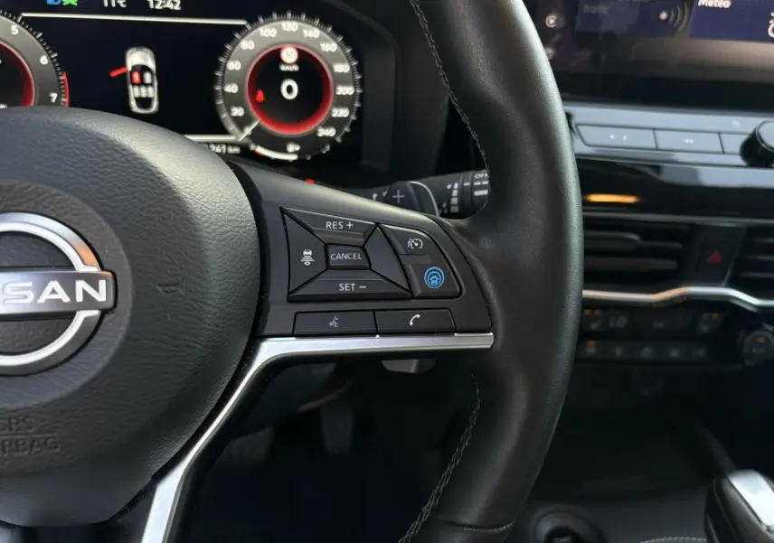 Gros plan sur le volant noir du Nissan Juke 2024 avec commandes de régulateur adaptatif et tableau de bord digital.