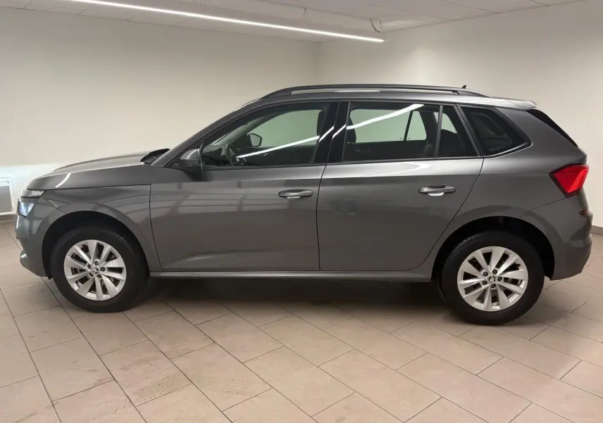 Vue de profil côté gauche d'un Skoda Kamiq 2023 gris graphite métallisé avec jantes alliage en intérieur neutre.