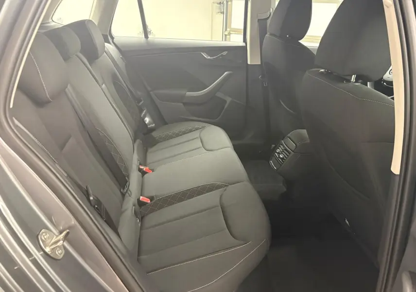 Vue intérieure côté arrière gauche du Skoda Kamiq 2023, sièges tissu noirs avec surpiqûres contrastées.