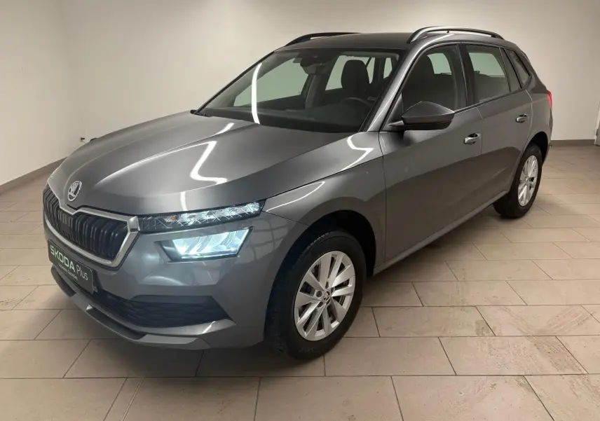 SKODA KAMIQ 1.0 TSI 2023 gris graphite, vue 3/4 avant droit avec phares allumés en intérieur.