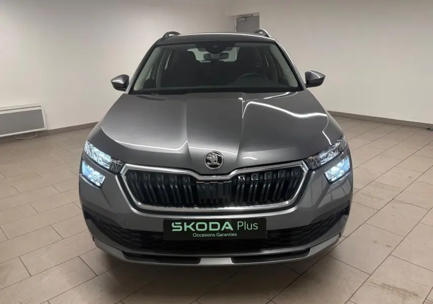 Vue avant d'un Skoda Kamiq 2023 gris graphite avec calandre noire et phares allumés en intérieur.