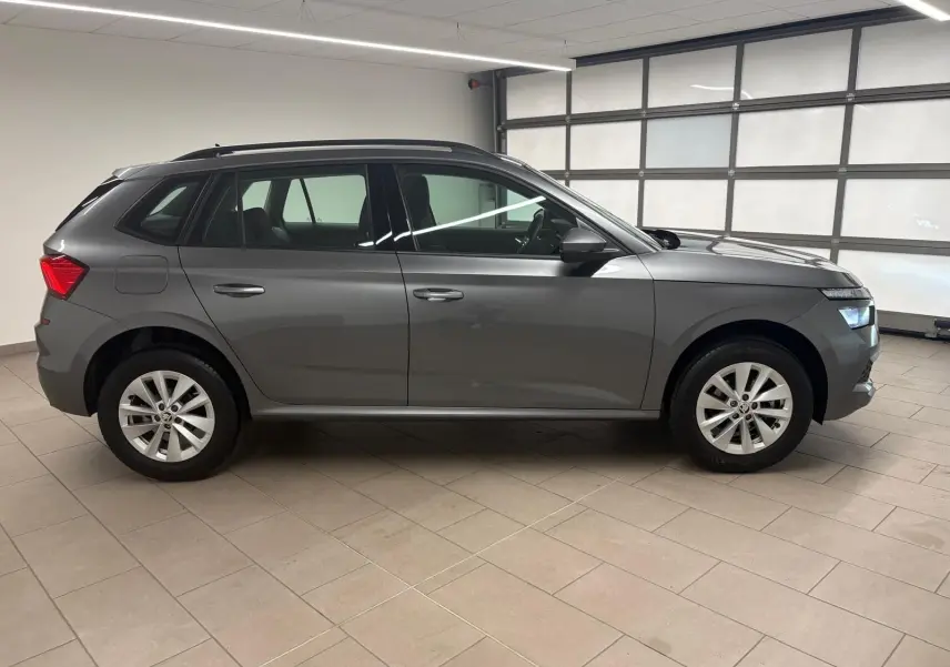 Vue de profil côté gauche d'un Skoda Kamiq 2023 gris graphite métallisé avec jantes alliage en intérieur lumineux.