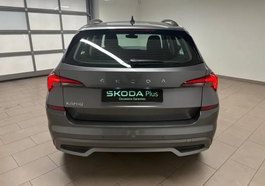 Vue arrière d'un Skoda Kamiq 2023 gris graphite avec feux LED et logo ŠKODA bien visibles dans un garage.