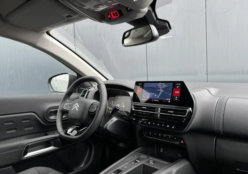 Vue intérieure côté conducteur du Citroën C5 Aircross 2025, tableau de bord noir avec écran tactile et volant multifonction.