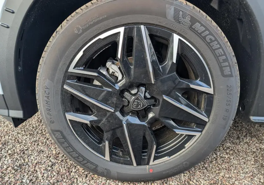 Gros plan sur la jante alliage noire et diamantée 19'' du Peugeot 3008 blanc hybride GT, avec logo Peugeot central.