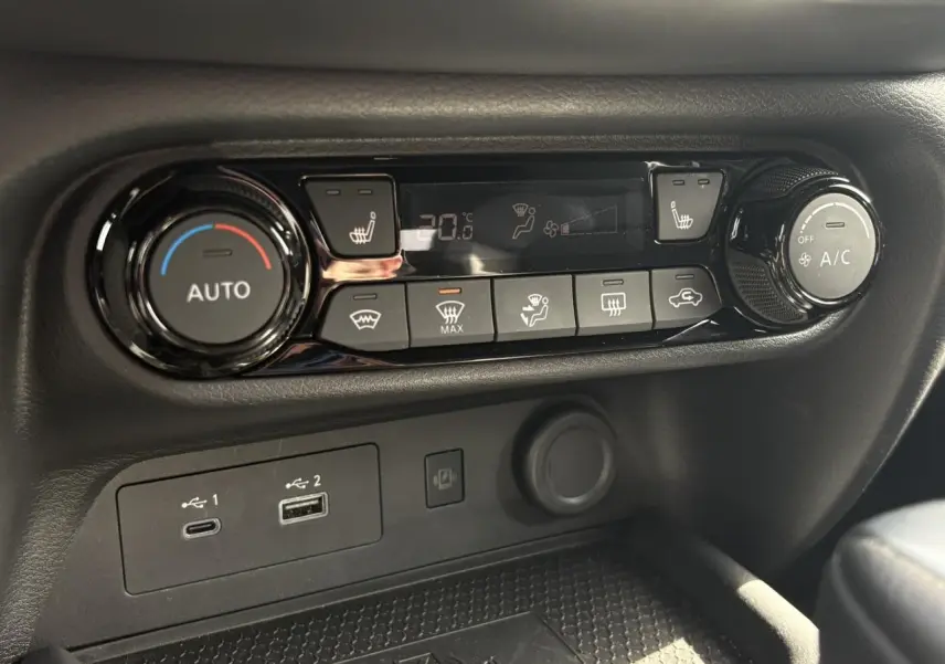 Gros plan sur la console centrale du Nissan Juke 2025, montrant les commandes de climatisation et ports USB.
