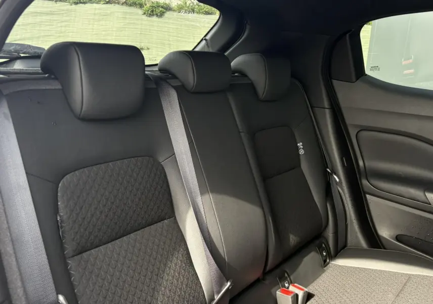 Vue intérieure du siège arrière droit du Nissan Juke 2025, avec sellerie noire et ceintures grises visibles.