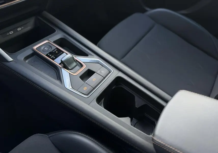 Gros plan sur la console centrale noire avec levier de vitesse automatique et accoudoir avant gris clair du CUPRA Formentor.