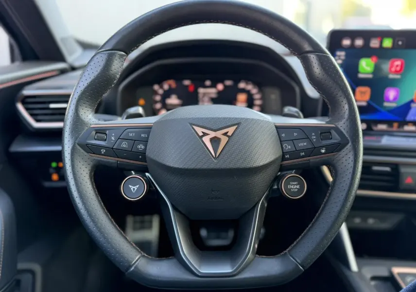 Gros plan sur le volant cuir noir perforé du CUPRA Formentor 2025 avec logo cuivre et commandes intégrées.