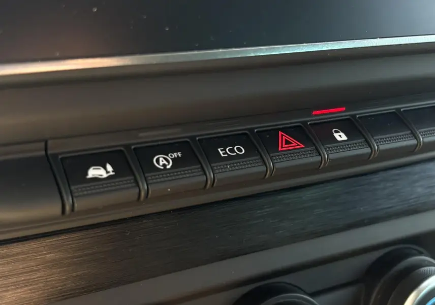 Gros plan sur les boutons de commande du tableau de bord noir du Nissan Primastar Combi 2025, avec bouton ECO et alerte.