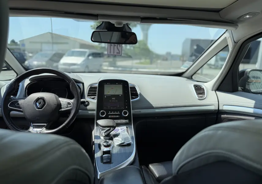 Vue intérieure avant de la Renault Espace V noire, mettant en valeur le tableau de bord moderne avec écran tactile et volant cuir.