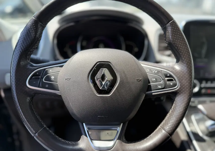 Gros plan sur le volant en cuir noir du Renault Espace V, avec commandes intégrées et logo central brillant.