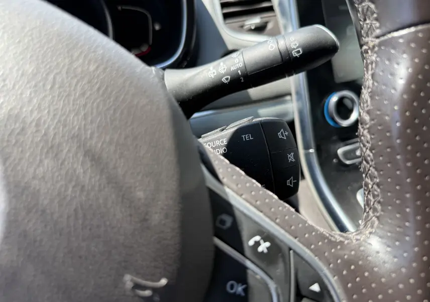 Gros plan sur la commande au volant perforé noir du Renault Espace V 1.6 DCI 160 Initiale Paris, avec boutons audio et téléphone.
