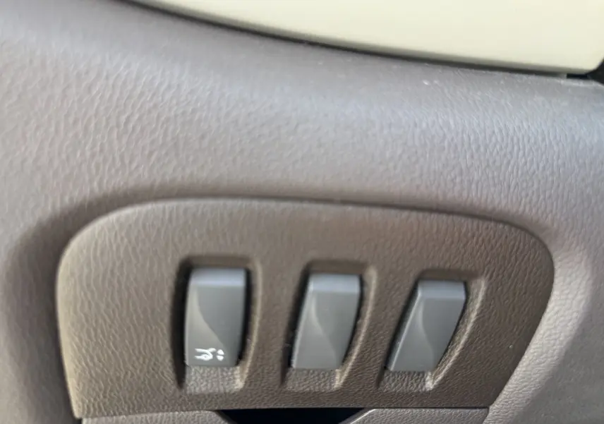 Gros plan sur les commandes de réglage électrique des sièges en cuir marron du Renault Espace V noir, côté gauche.