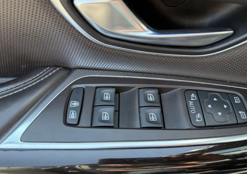Gros plan sur les commandes de lève-vitres et rétroviseurs côté gauche en cuir noir perforé d’un Renault Espace V.