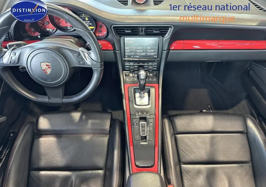 Intérieur de Porsche 911 (991) Carrera 4 PDK vu de dessus, cuir noir et inserts rouges brillants sur la console centrale.