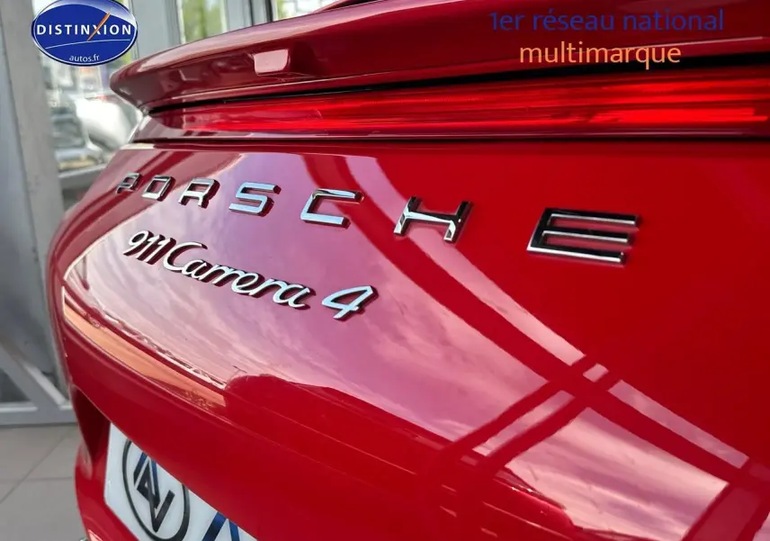 Gros plan sur l'arrière rouge brillant d'une Porsche 911 Carrera 4 avec logo et becquet intégré.