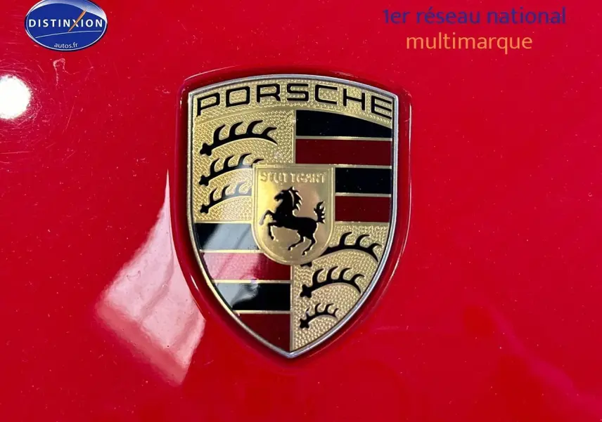 Gros plan sur l’écusson Porsche doré sur la carrosserie rouge vif d’une 911 (991) Carrera 4 PDK de 2013.