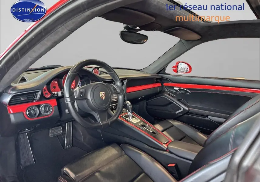 Intérieur noir et rouge de Porsche 911 (991) Carrera 4 PDK vu côté conducteur, soulignant le tableau de bord et la console centrale.