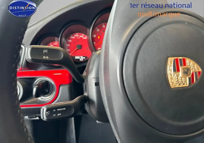 Gros plan sur le volant Porsche avec cadrans rouges et insert rouge brillant du tableau de bord d'une 911 Carrera 4 PDK rouge.