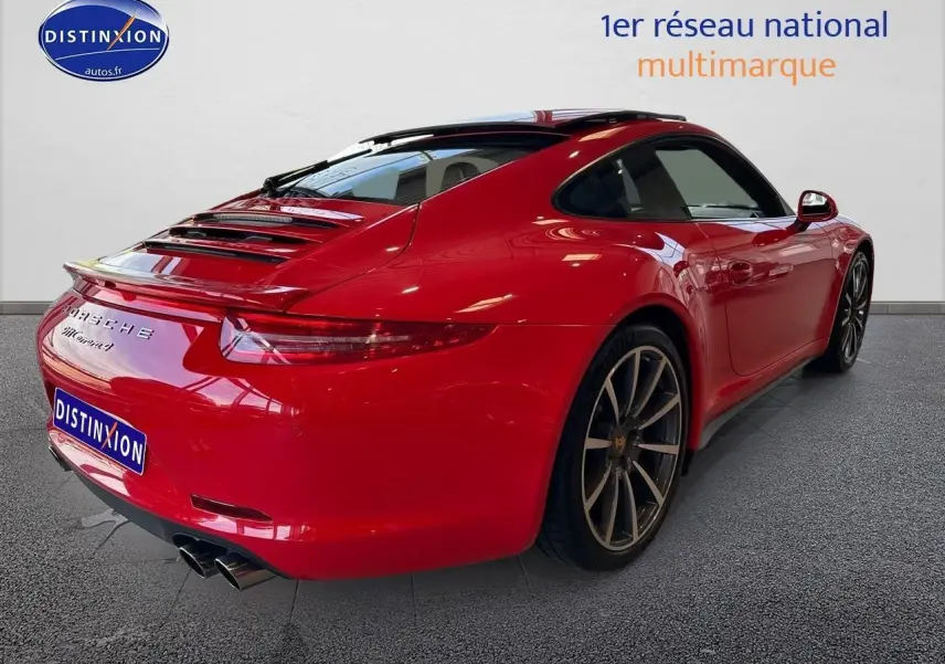 Vue 3/4 arrière droite d'une Porsche 911 Carrera 4 rouge avec échappement sport et jantes alu foncées.