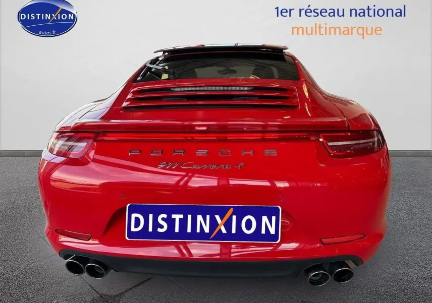 Vue arrière d'une Porsche 911 Carrera 4 rouge avec échappement sport et becquet arrière visible.