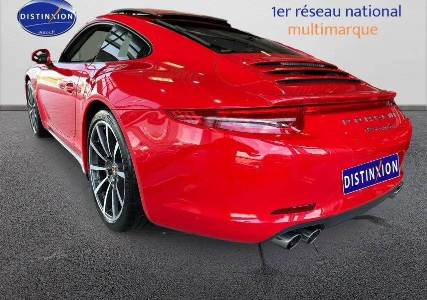 Vue 3/4 arrière droite d'une Porsche 911 Carrera 4 rouge avec échappement sport et jantes alu.