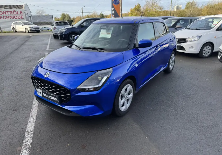 Suzuki Swift 1.2 Hybrid Privilege bleu vue 3/4 avant droit sur parking avec plaque occasion visible