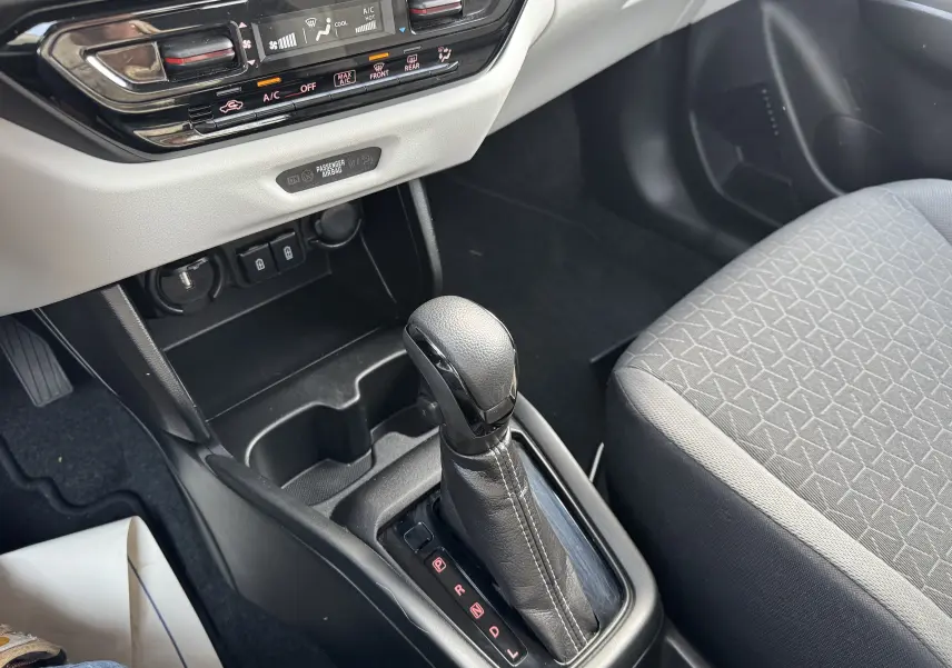 Le levier de vitesse automatique en cuir noir de la Suzuki Swift 1.2 Hybrid Privilege 2025, avec console centrale et siège tissu gris.
