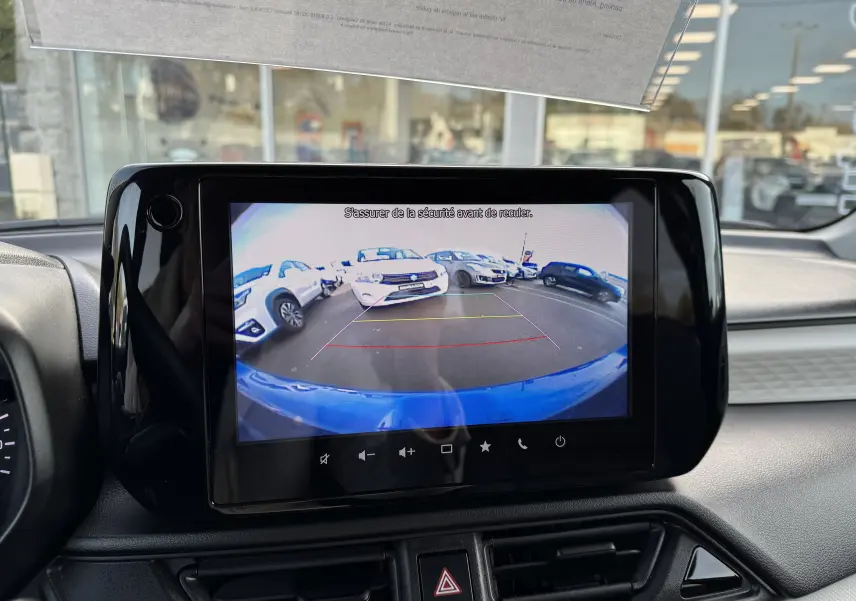 Écran central affichant la caméra de recul d'une Suzuki Swift bleue, vue arrière avec lignes de guidage colorées.