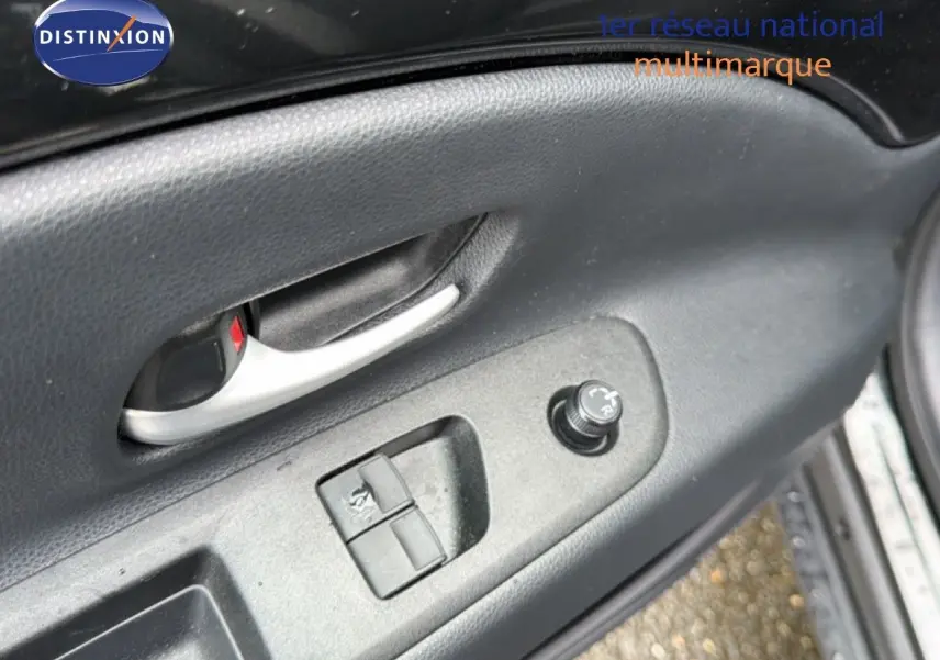 Détail de la porte côté gauche de la Toyota Aygo X noire 2025, montrant la poignée intérieure et les commandes des vitres et rétroviseurs.