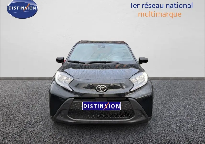Vue de face d'une Toyota Aygo X noire 2025 avec calandre large et phares anguleux, sur fond neutre avec logo Distinxion.