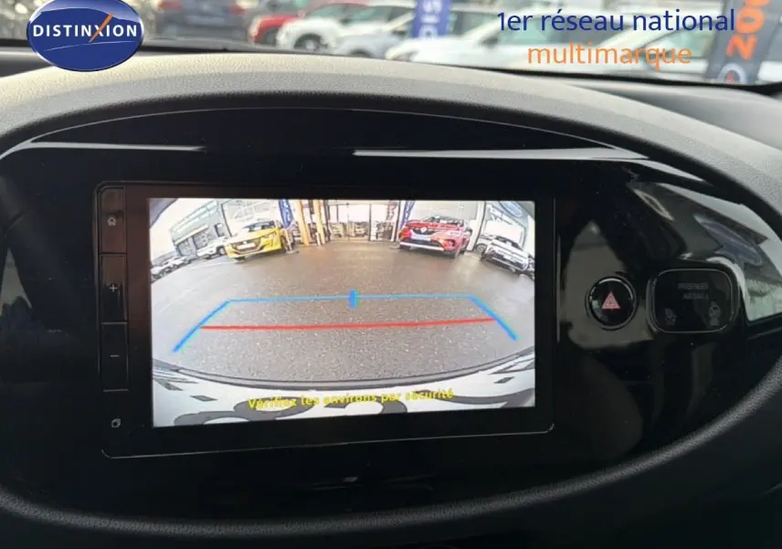 Écran central de la Toyota Aygo X 2025 montrant la caméra de recul avec repères colorés sur fond noir brillant.