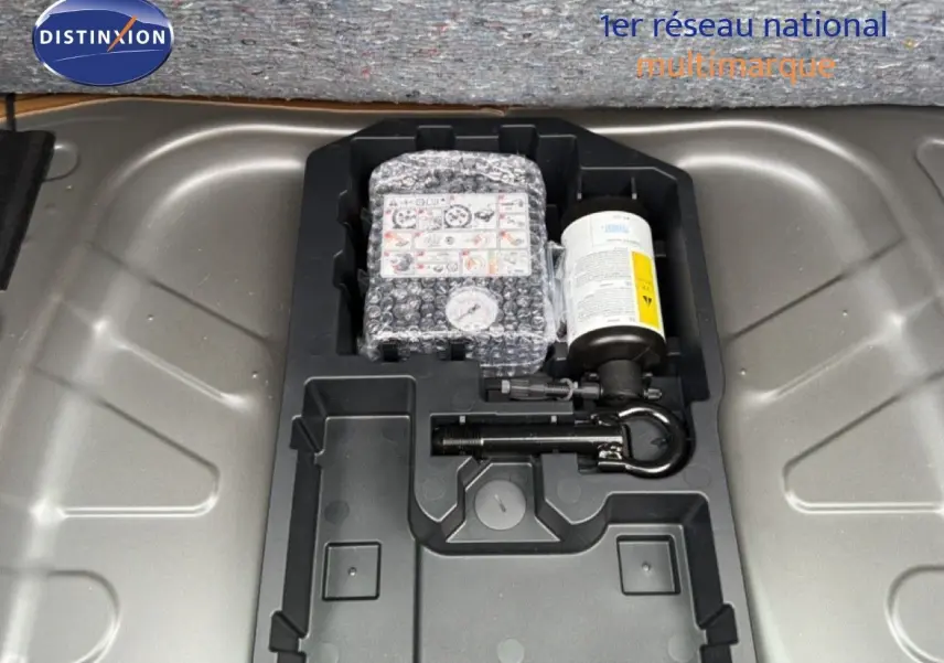 Gros plan sur le rangement sous coffre de la Toyota Aygo X 2025, montrant le kit de réparation pneus intégré.