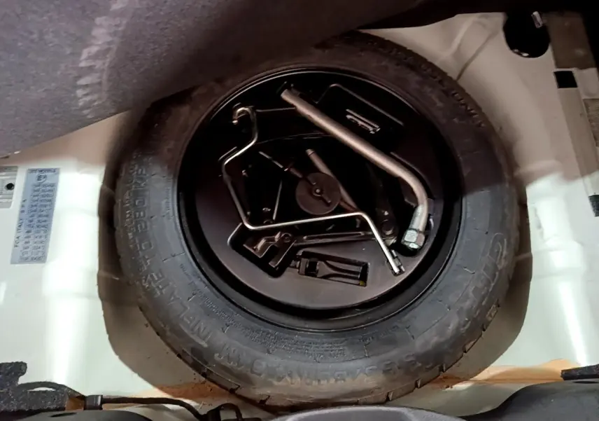 Vue rapprochée de la roue de secours et des outils dans le coffre d’une Fiat 500 blanche hybride 2021.