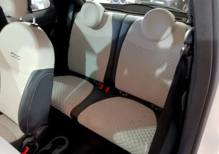 Vue intérieure sur la banquette arrière beige et noire de la FIAT 500 Hybrid 2021, avec détails matelassés et appuie-têtes ronds.