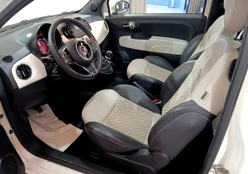Vue intérieure côté conducteur de la Fiat 500 Dolcevita 2021, sièges cuir bicolores beige et noir, volant multifonctions.