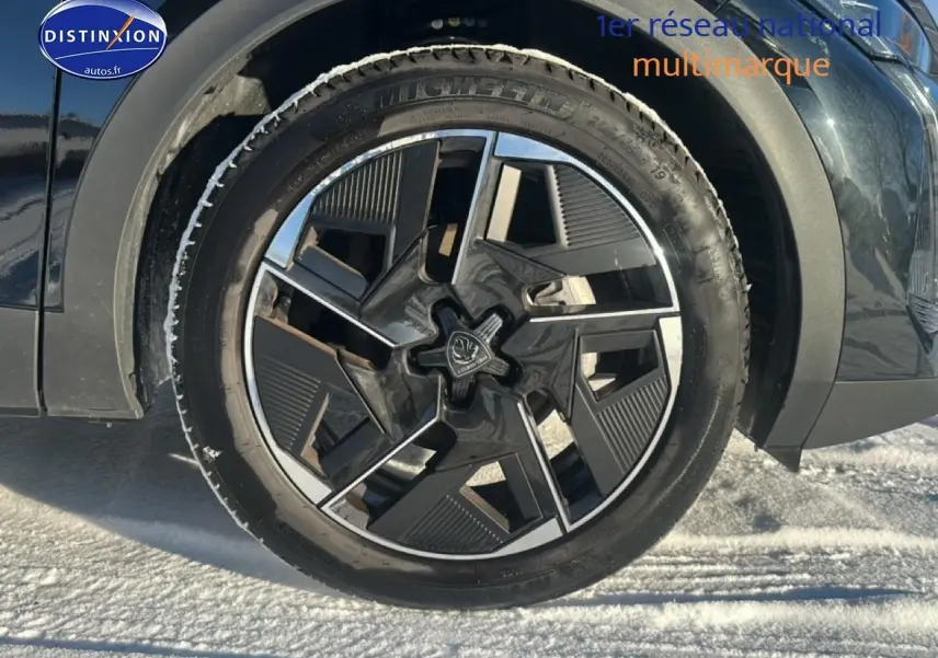 Gros plan sur la roue avant gauche noire de la Peugeot 408 Hybrid 145 GT e-dcs6 avec jante alu design moderne.