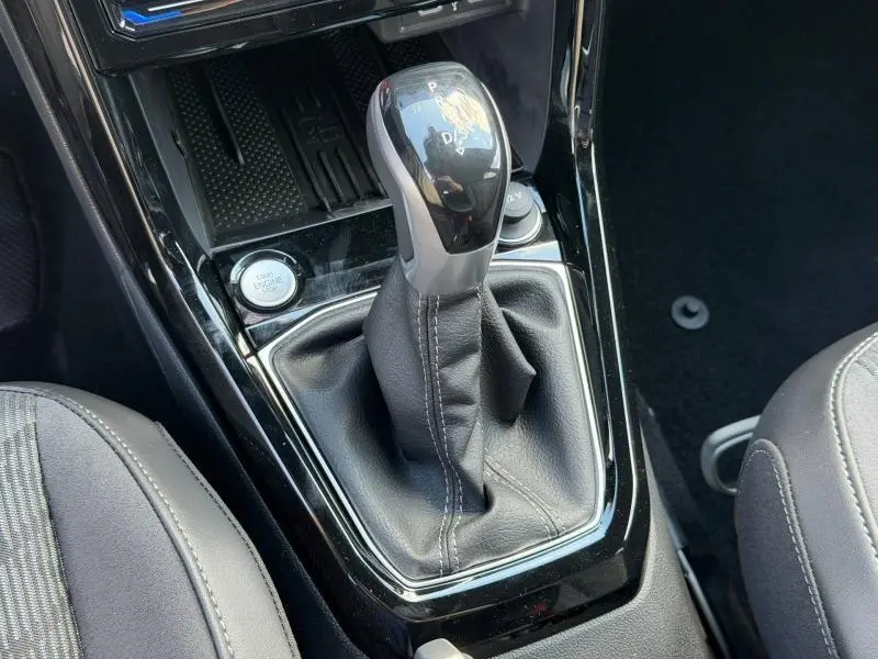 Gros plan sur le levier de vitesses automatique DSG7 noir et argenté du Volkswagen T-Cross 1.0 TSI R-Line, intérieur cuir noir.