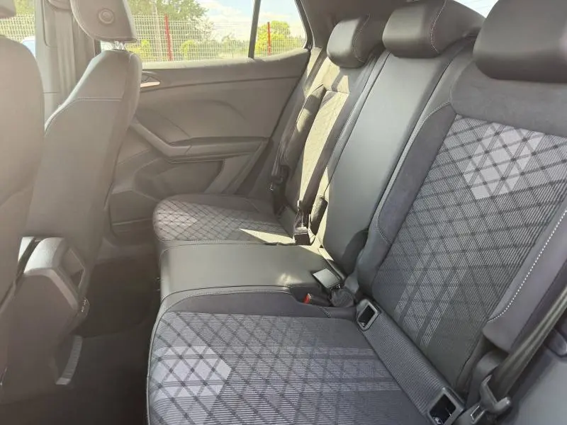 Vue intérieure côté droit montrant la banquette arrière en tissu gris à motifs géométriques du Volkswagen T-Cross noir nacré 2026.