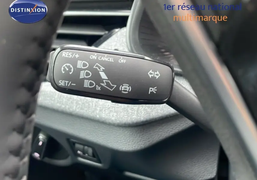 Gros plan sur la commande de régulateur de vitesse au volant d'un Skoda Kamiq gris graphite intérieur noir.